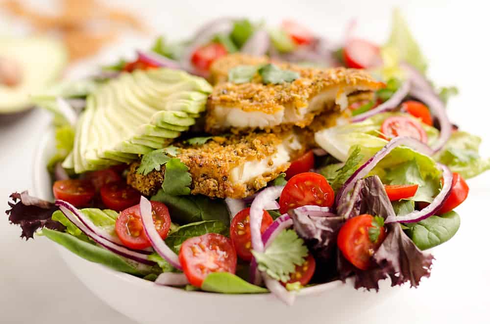 Southwest Tortilla Crusted Tilapia Salad is an easy and healthy dinner idea with a bed of mixed greens topped with tomatoes, avocado, red onion, Tortilla Crusted Tilapia and a homemade Chipotle Lime Dressing. 