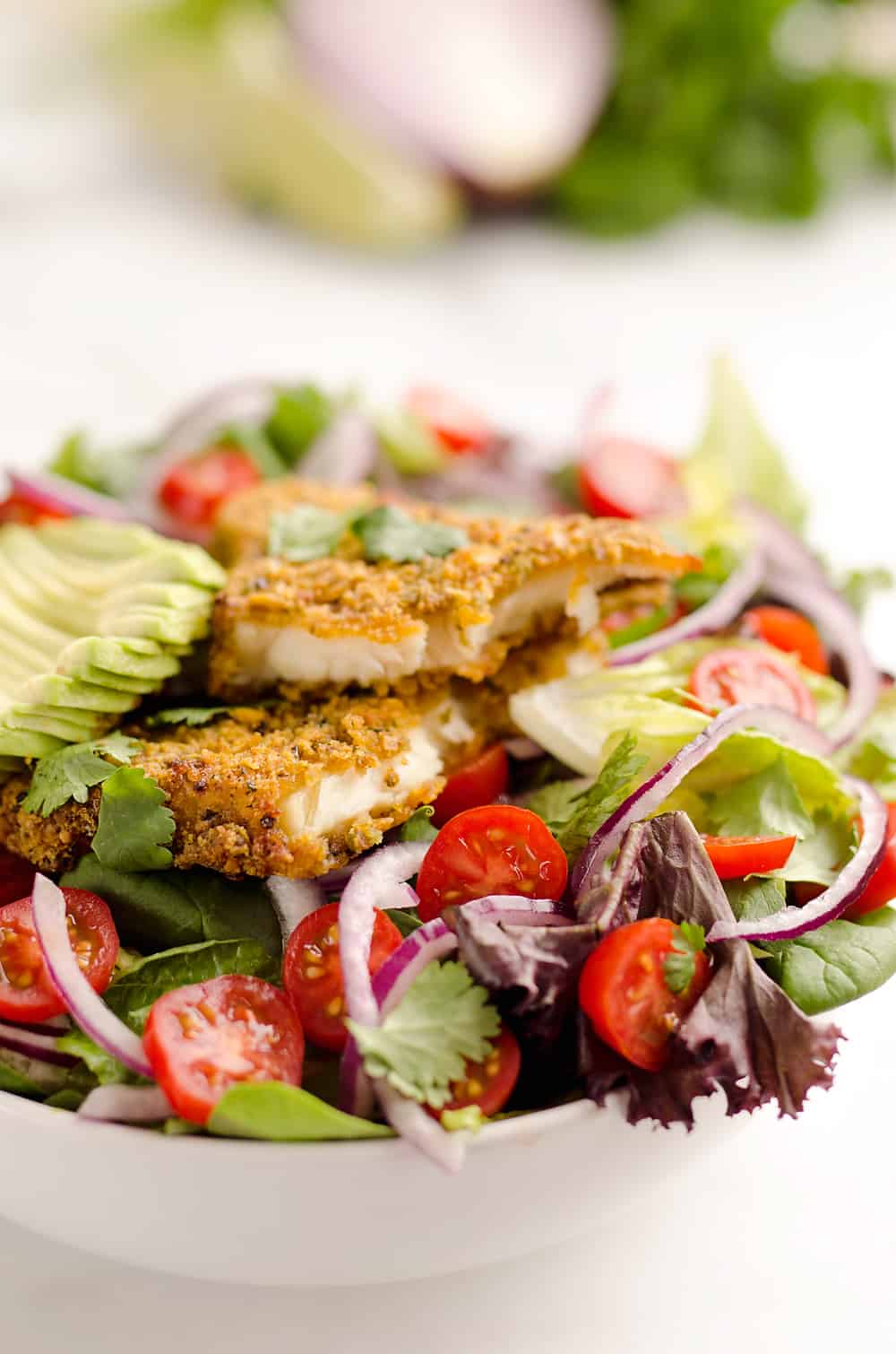 Southwest Tortilla Crusted Tilapia Salad is an easy and healthy dinner idea with a bed of mixed greens topped with tomatoes, avocado, red onion, Tortilla Crusted Tilapia and a homemade Chipotle Lime Dressing. 