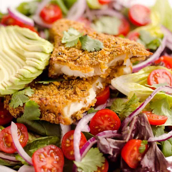 Southwest Tortilla Crusted Tilapia Salad is an easy and healthy dinner idea with a bed of mixed greens topped with tomatoes, avocado, red onion, Tortilla Crusted Tilapia and a homemade Chipotle Lime Dressing.