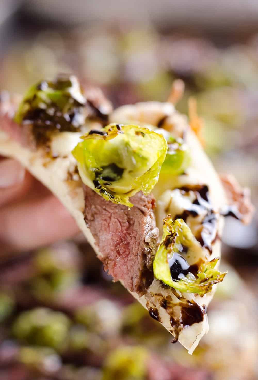 Steak, Goat Cheese & Roasted Brussels Sprout Flatbread is a hearty dinner idea bursting with bold flavors. A chewy naan bread is topped with goat cheese, grilled steak, roasted brussels sprout leaves and a balsamic glaze for a delicious and unique recipe you will make again and again!