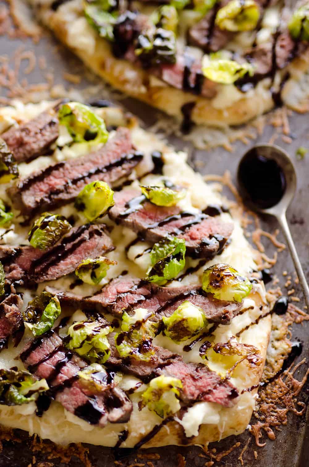 Steak, Goat Cheese & Roasted Brussels Sprout Flatbread is a hearty dinner idea bursting with bold flavors. A chewy naan bread is topped with goat cheese, grilled steak, roasted brussels sprout leaves and a balsamic glaze for a delicious and unique recipe you will make again and again!