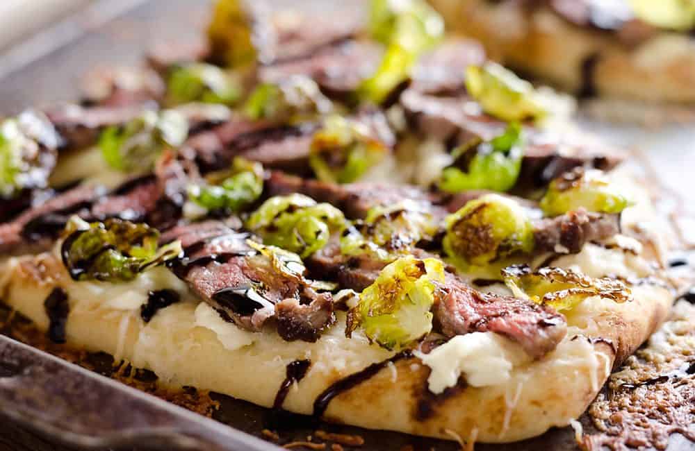 Steak, Goat Cheese & Roasted Brussels Sprouts Flatbread on sheet pan with browned cheese