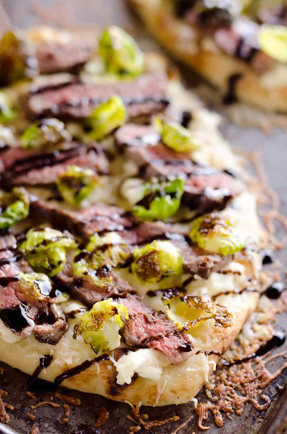 Steak, Goat Cheese & Roasted Brussels Sprout Flatbread is a hearty dinner idea bursting with bold flavors. A chewy naan bread is topped with goat cheese, grilled steak, roasted brussels sprout leaves and a balsamic glaze for a delicious and unique recipe you will make again and again!