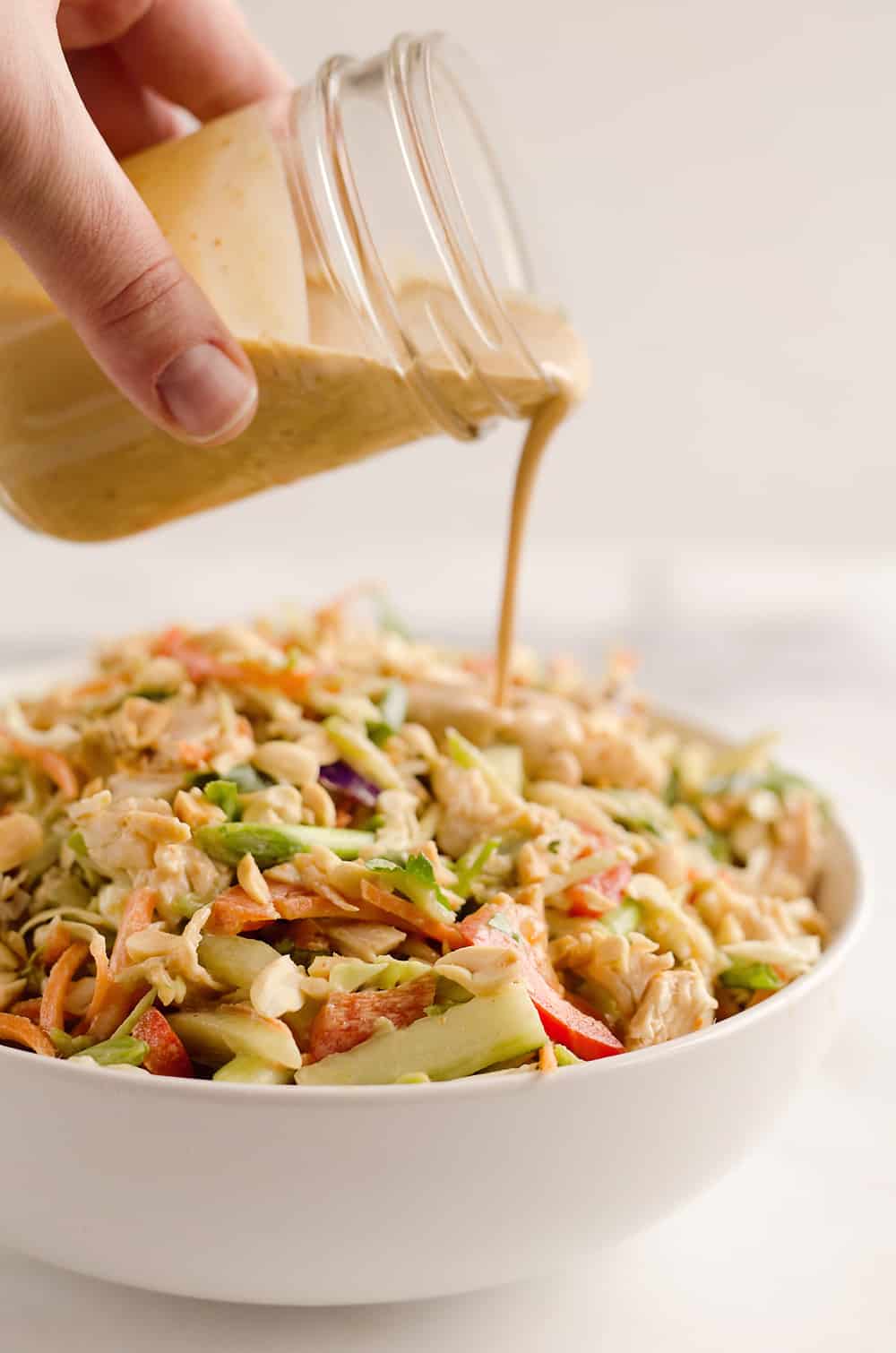 Thai Peanut Chicken Crunch Slaw Salad is an easy & healthy cold salad that is loaded with fresh flavor and crunch! Coleslaw and broccoli slaw are tossed with cucumbers, carrots, bell peppers and chicken and dressed with a homemade Thai Peanut Sauce for a hearty serving of vegetables in a salad you will love.