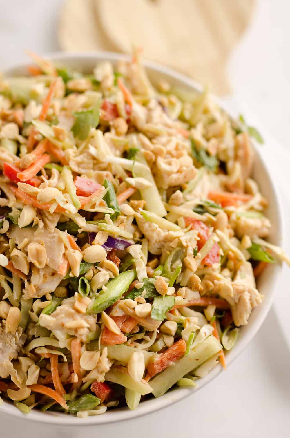 Thai Peanut Chicken Crunch Slaw Salad is an easy & healthy cold salad that is loaded with fresh flavor and crunch! Coleslaw and broccoli slaw are tossed with cucumbers, carrots, bell peppers and chicken and dressed with a homemade Thai Peanut Sauce for a hearty serving of vegetables in a salad you will love.