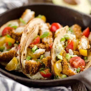 Tortilla Crusted Fish Tacos with Avocado Crema are a healthy and easy weeknight meal you can make in just 20 minutes with your Airfryer! Crispy Tortilla Crusted Tilapia is layered in a grilled corn tortilla with avocado crema and fresh tomatoes for a flavorful dinner recipe the whole family will love.