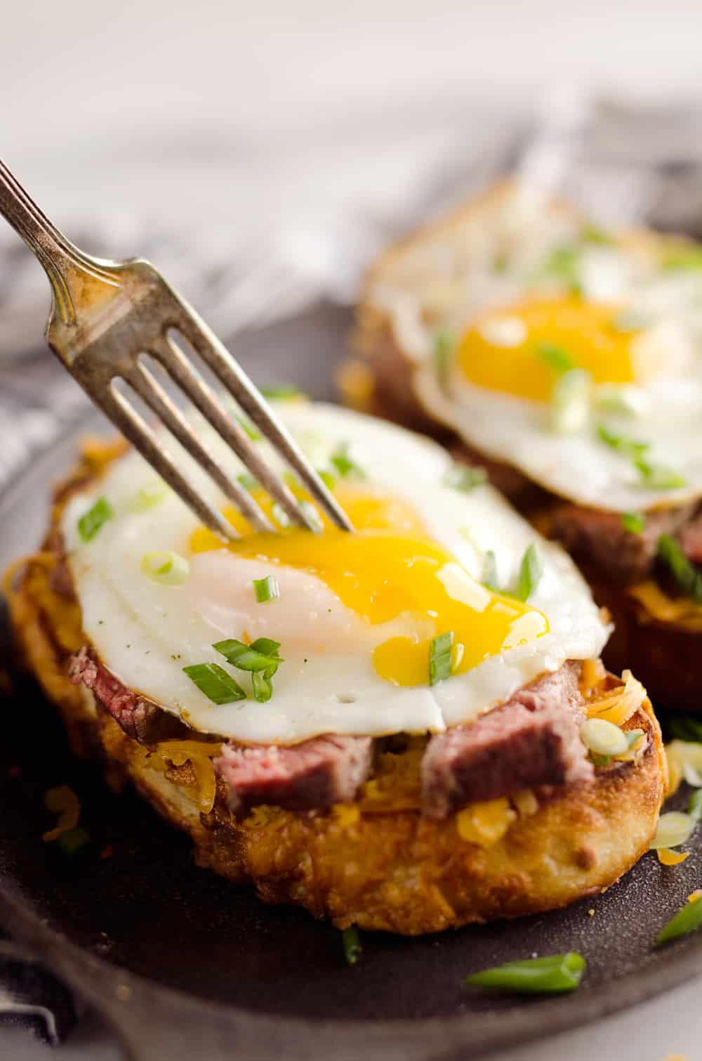 Breakfast Steak & Cheddar Toasts are a rich and decadent recipe filled with all the best parts of brunch. Tender steak is layered on top of a cheesy toast and topped with a sunny side up egg and scallions. 