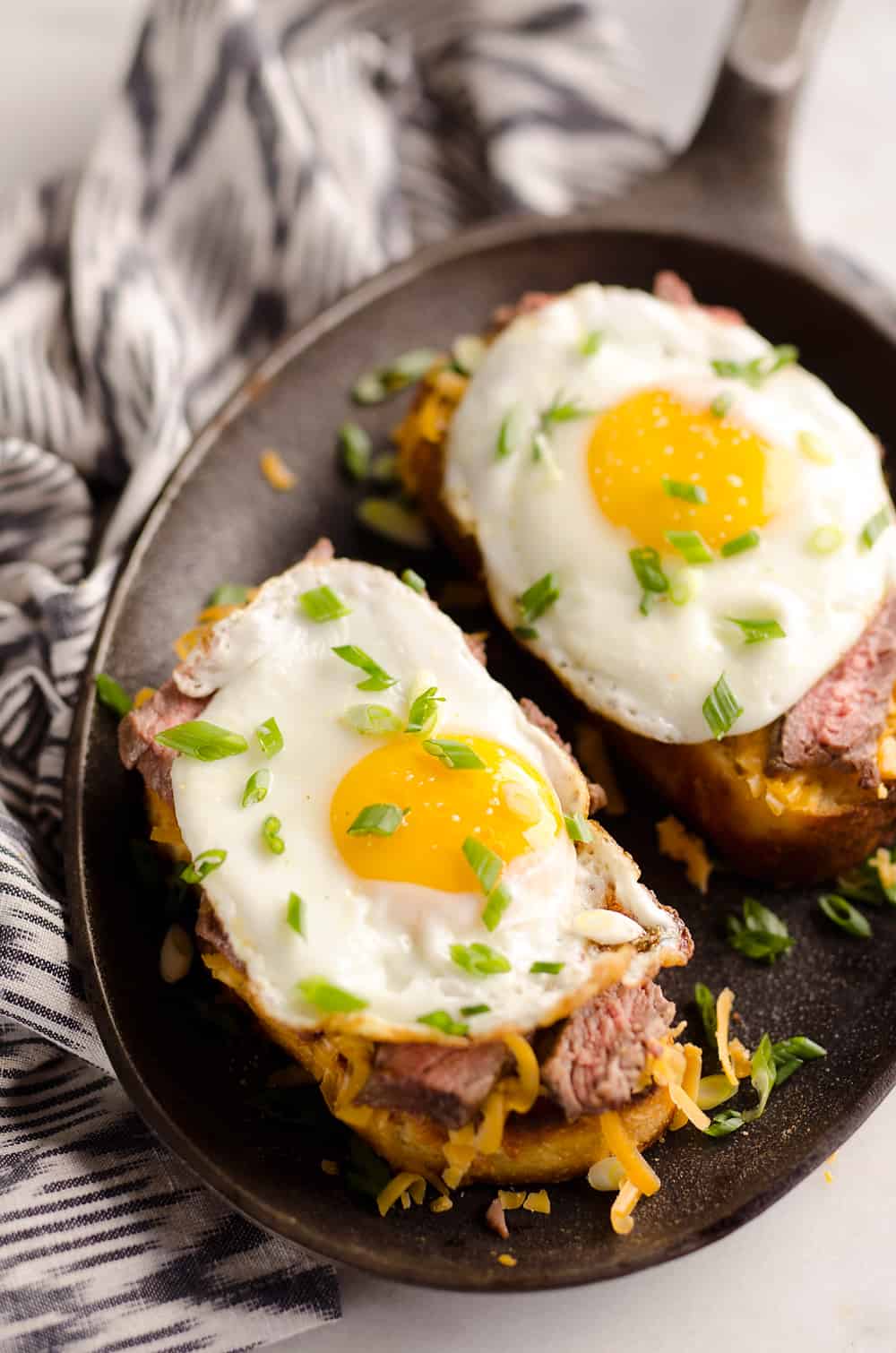 Breakfast Steak & Cheddar Toasts are a rich and decadent recipe filled with all the best parts of brunch. Tender steak is layered on top of a cheesy toast and topped with a sunny side up egg and scallions. 