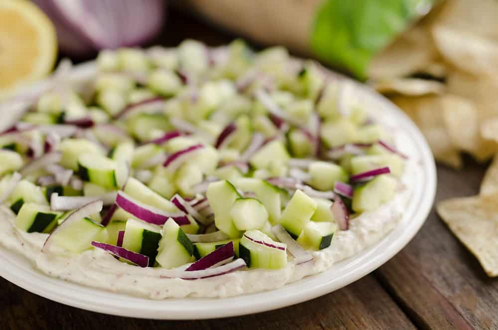 Creamy Cucumber Layered Dip is an easy 10 minute recipe perfect for a flavorful summer snack. A lightened up layer of creamy goodness is topped with fresh cucumbers and onions and served with Mission Organics Tortilla Chips for a wholesome dish you will love!