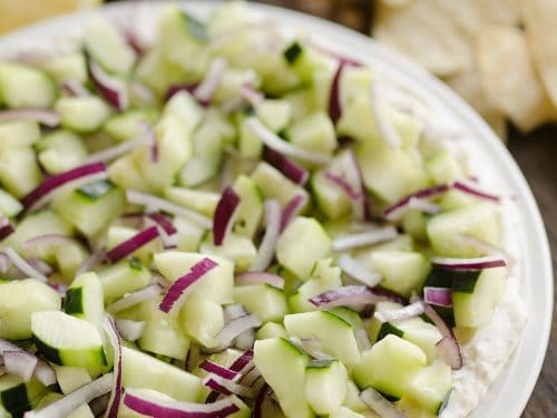 Creamy Cucumber Layered Dip is an easy 10 minute recipe perfect for a flavorful summer snack. A lightened up layer of creamy goodness is topped with fresh cucumbers and onions and served with Mission Organics Tortilla Chips for a wholesome dish you will love!