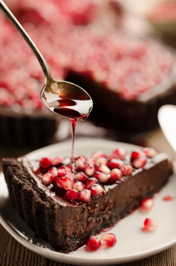 Salted Dark Chocolate Pomegranate Tart slice with pomegranate glaze drizzle