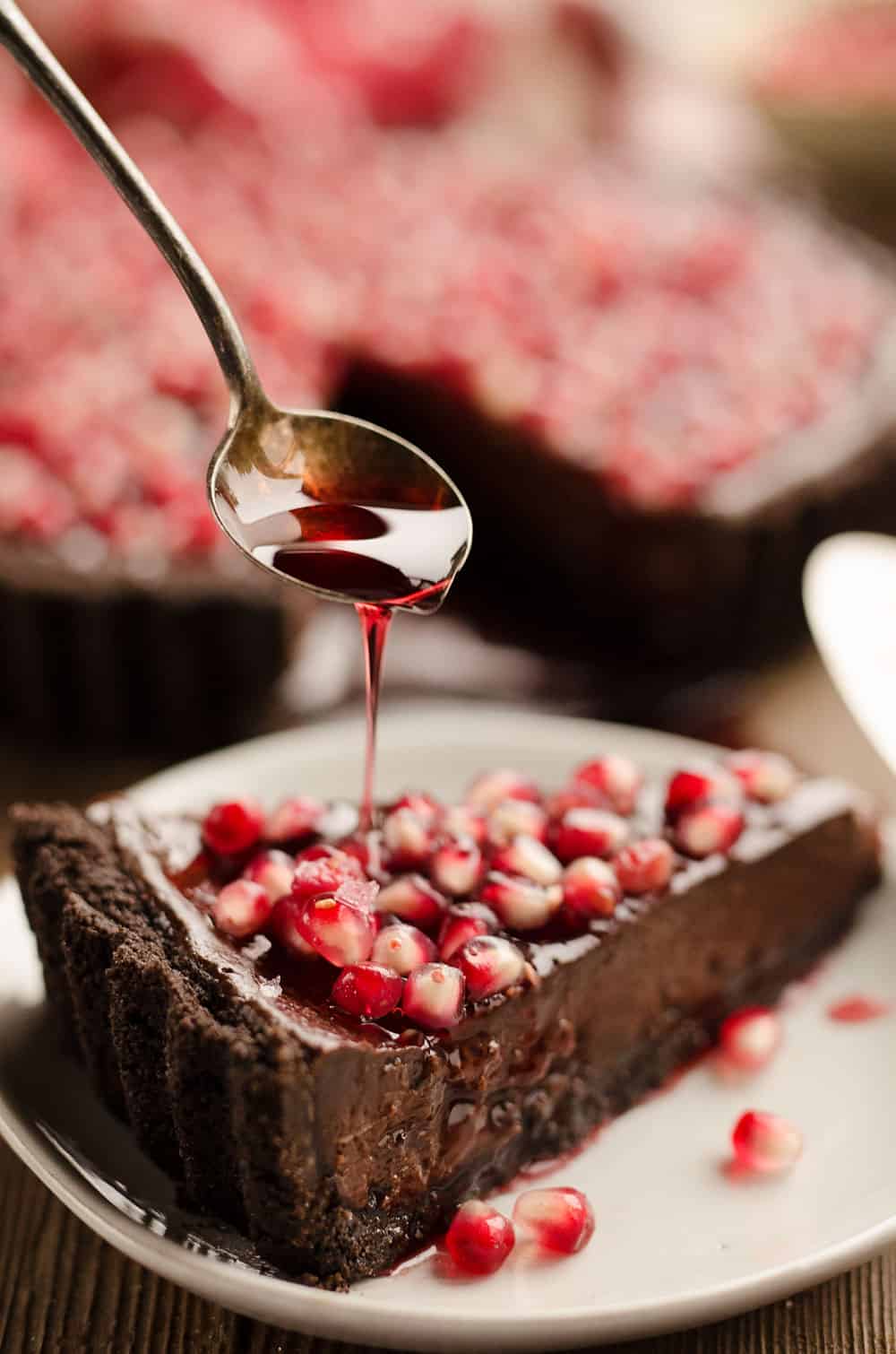 Salted Dark Chocolate Pomegranate Tart slice with pomegranate glaze drizzle