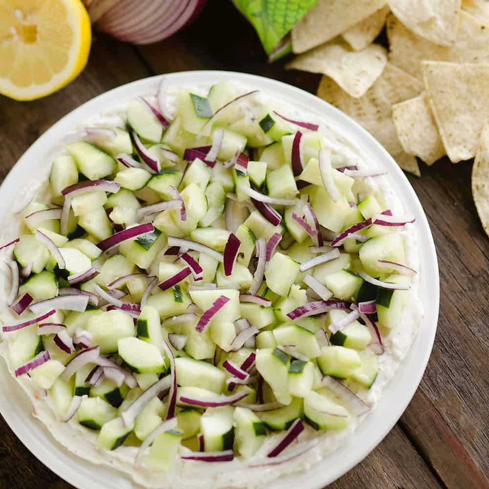 Creamy Cucumber Layered Dip is an easy 10 minute recipe perfect for a flavorful summer snack. A lightened up layer of creamy goodness is topped with fresh cucumbers and onions and served with Mission Organics Tortilla Chips for a wholesome dish you will love!