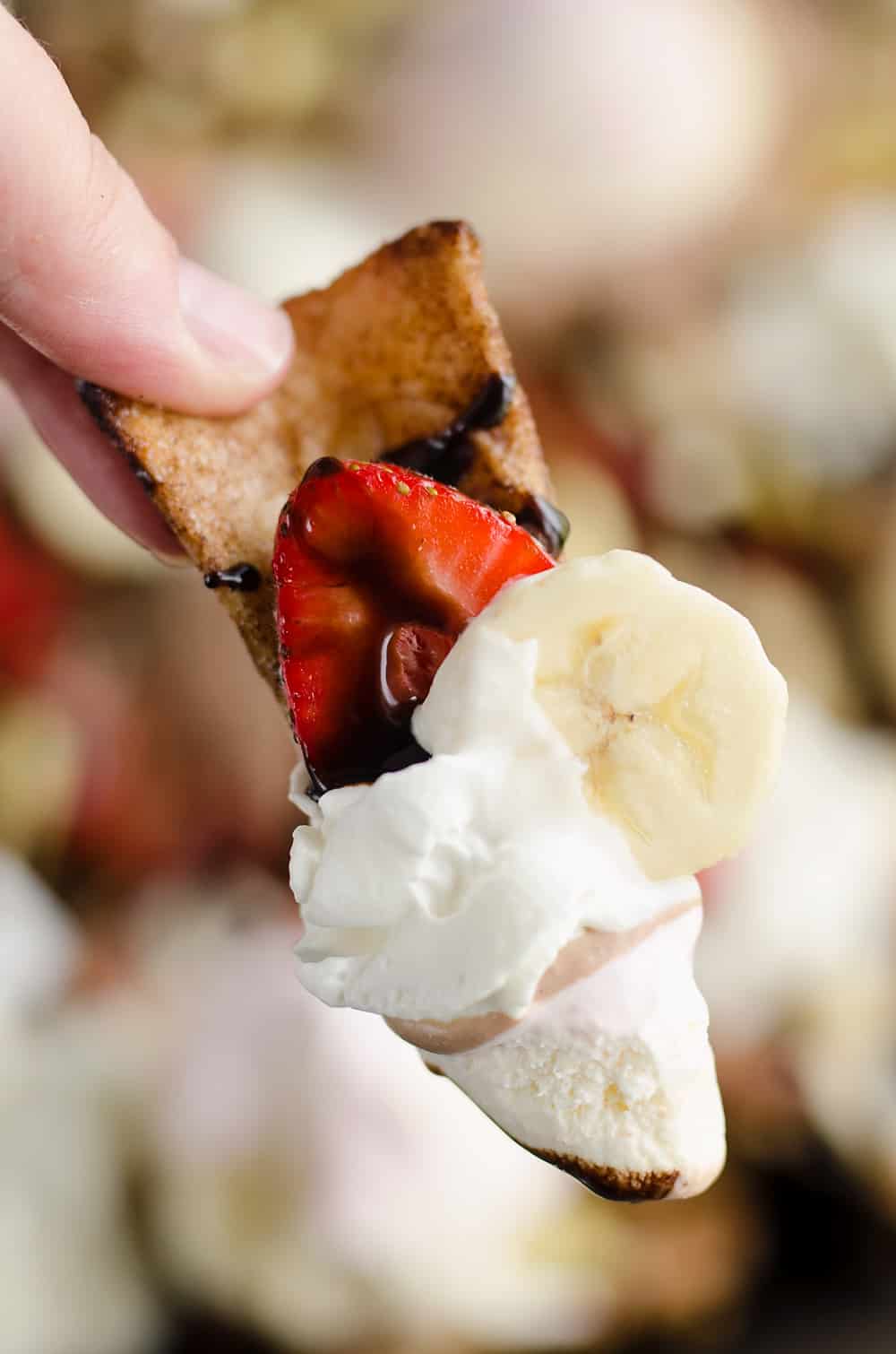 Ultimate Banana Split Dessert Nachos chip scooping up toppings