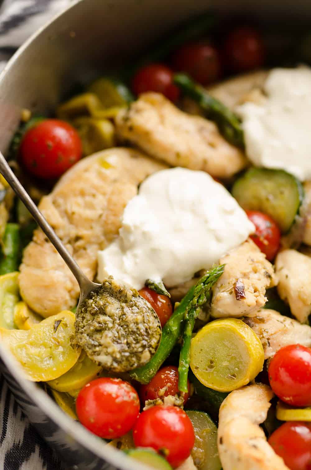 Summer Pesto Chicken & Vegetable Skillet in pan with scoop of pesto