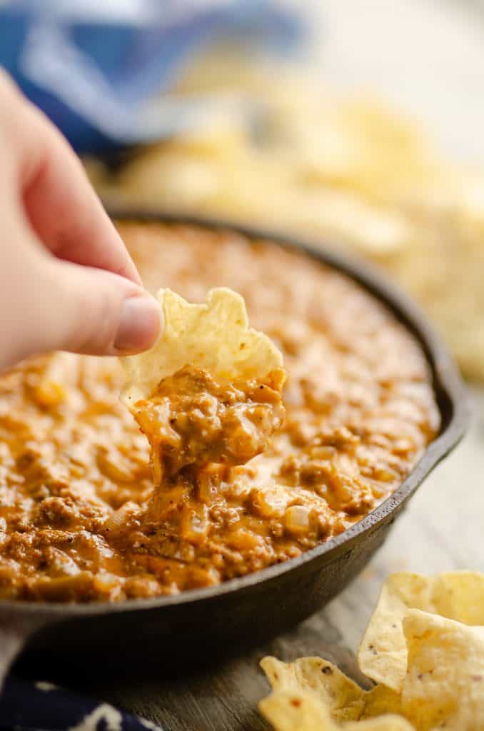 Light Queso Dip scooping cheesy dip