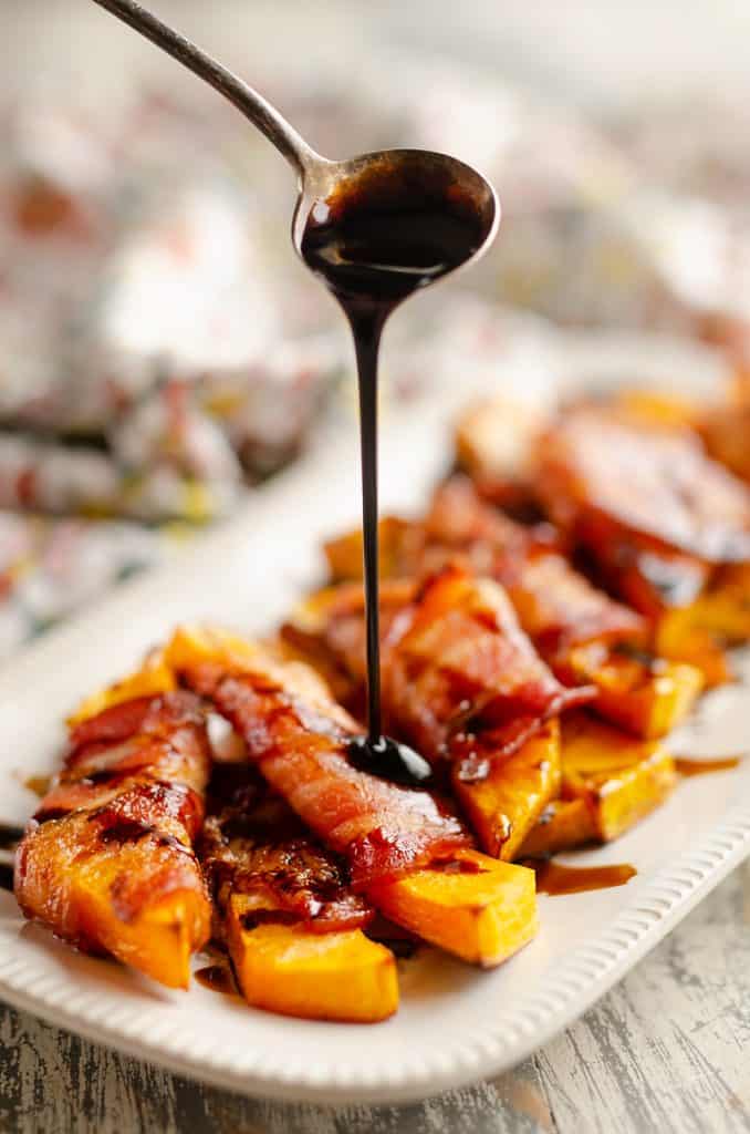 Balsamic Glazed Bacon Wrapped Squash with spoon drizzling glaze