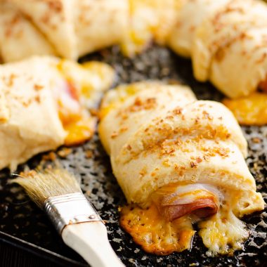 Hot Ham & Cheese Roll Ups on cookie sheet with brush