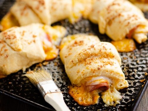 Hot Ham & Cheese Roll Ups on cookie sheet with brush