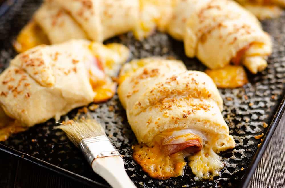 Hot Ham & Cheese Roll Ups on cookie sheet with brush