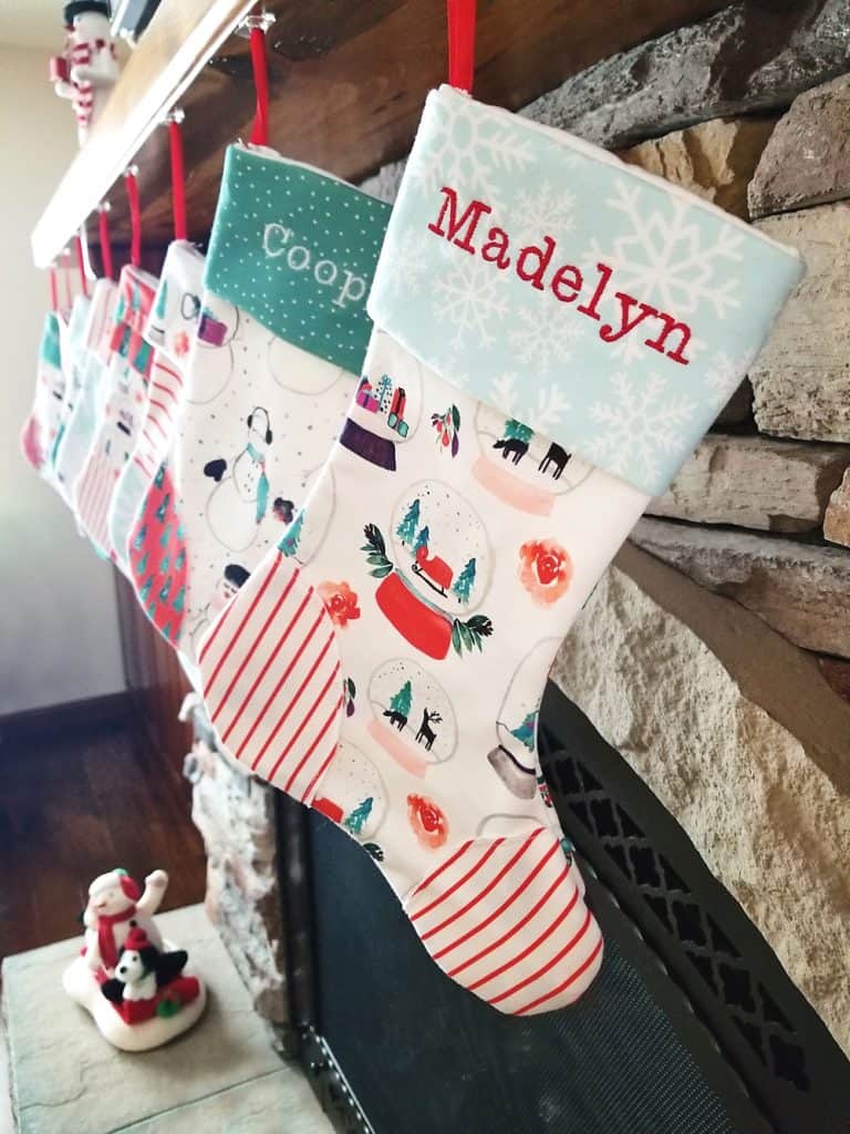 homemade personalized Christmas stockings hanging on fireplace mantel