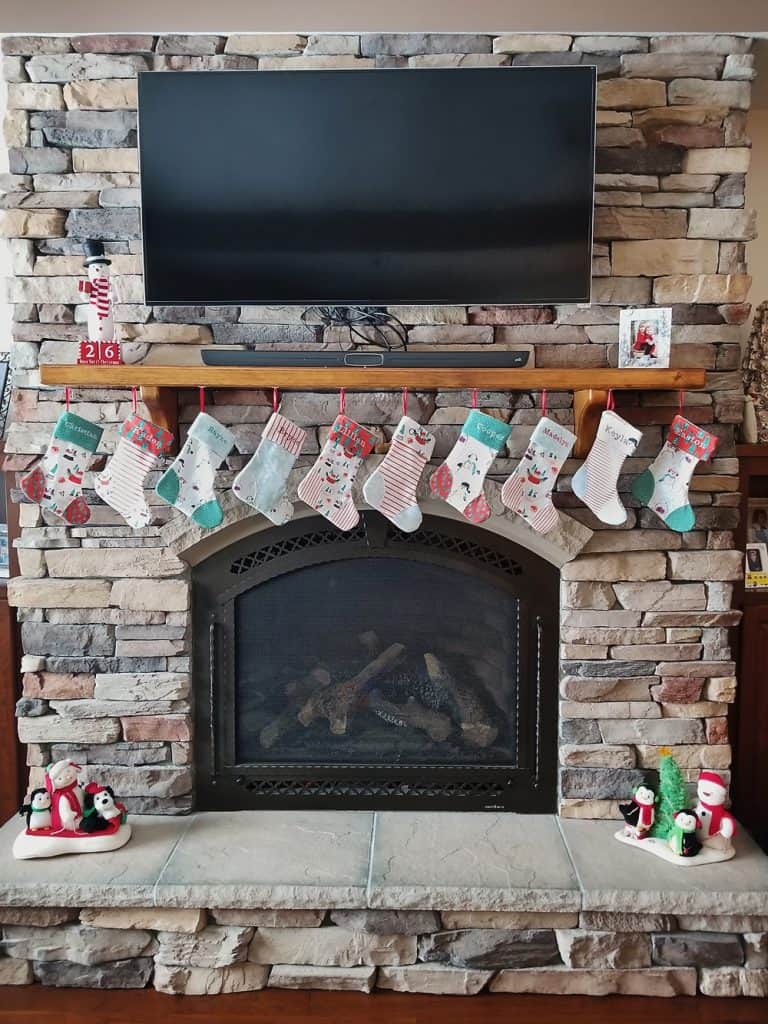homemade personalized Christmas stockings hanging on fireplace mantel