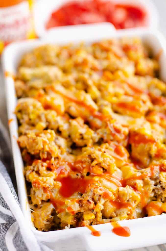 Pressure Cooker Buffalo Chicken Quinoa in dish topped with cheese and sauce