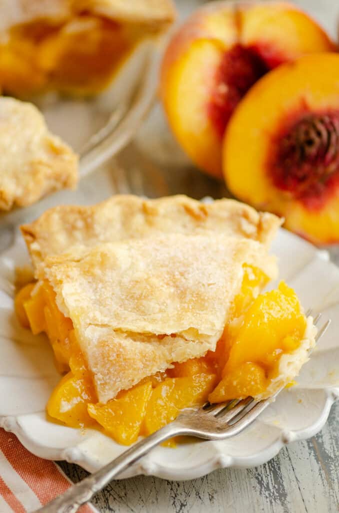 slice of peach pie on plate with bite on fork