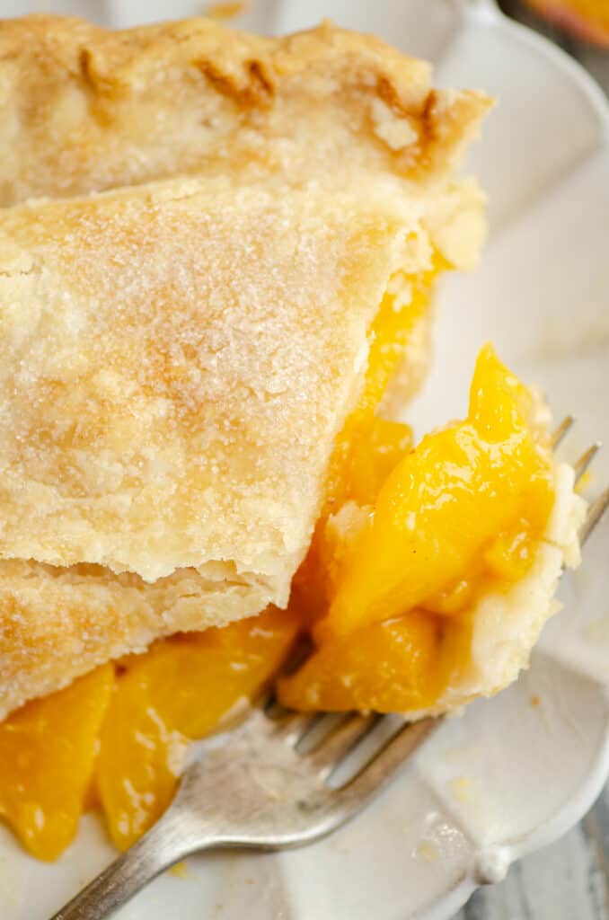 bite of peach pie on fork with slice