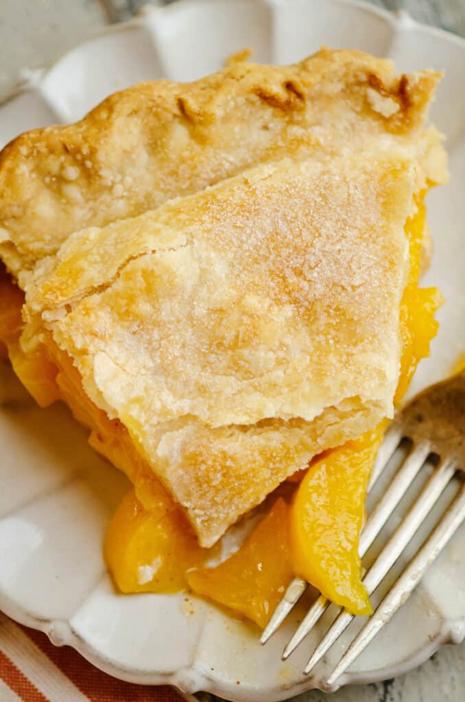 slice of peach pie on plate with fork
