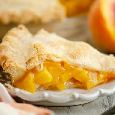 slice of peach pie on plate with peaches