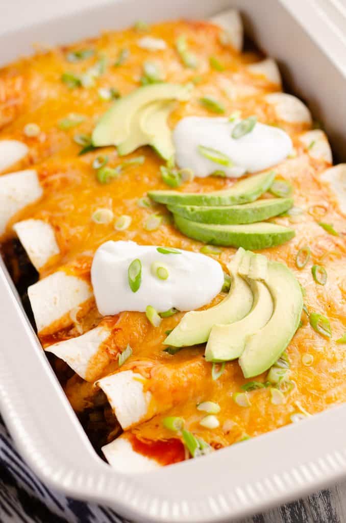 Black Bean & Squash Vegetarian Enchiladas topped with sour cream and avocado