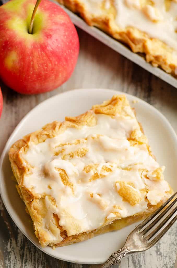 Glazed Apple Pie Bars on plate with fork and apple on table