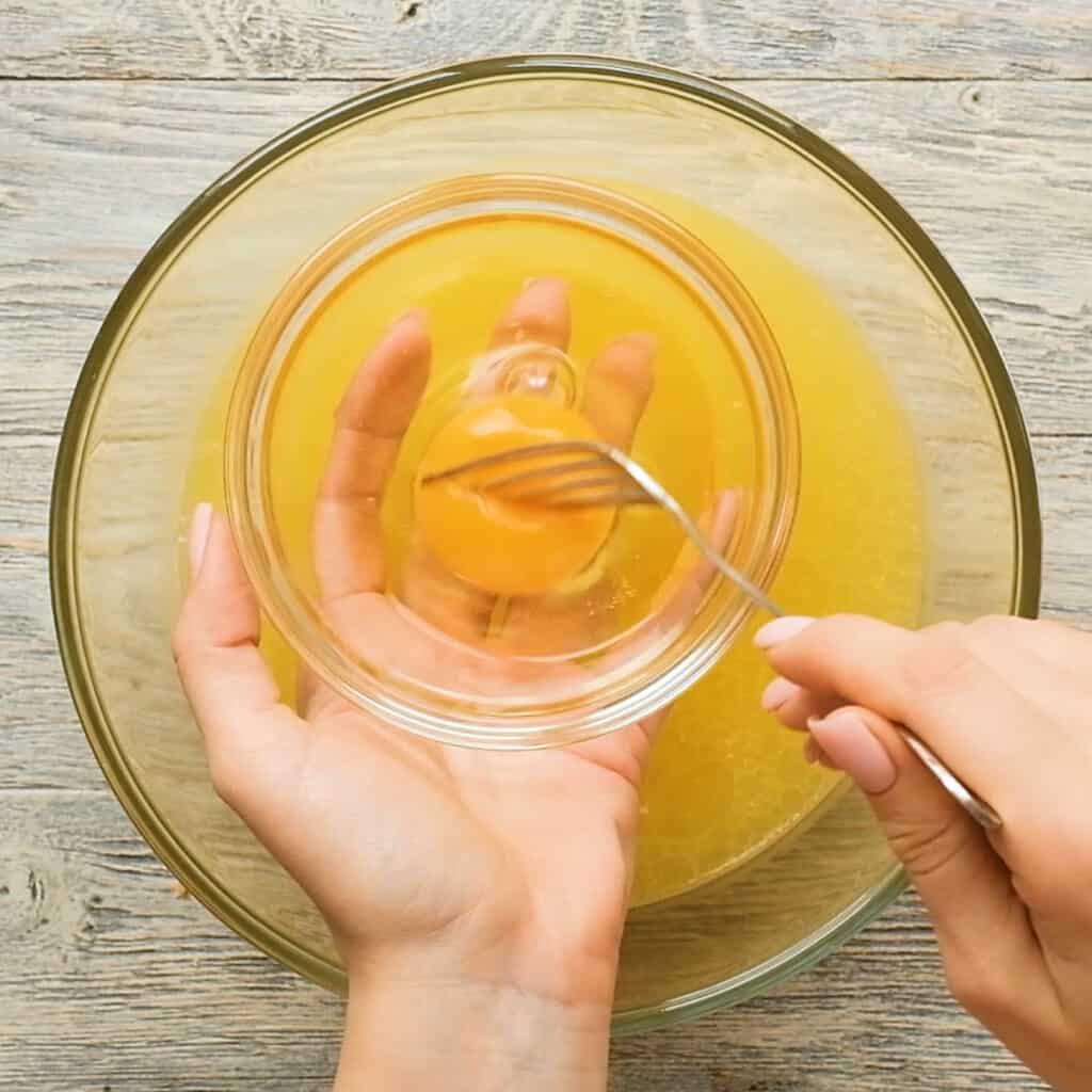 egg whisked in small bowl over broth