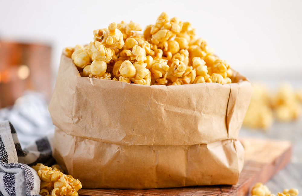 Microwave Caramel Popcorn in a brown paper bag on table with cloth napkin