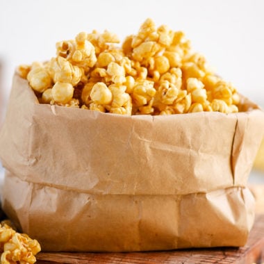 Microwave Caramel Popcorn in a brown paper bag on table with cloth napkin