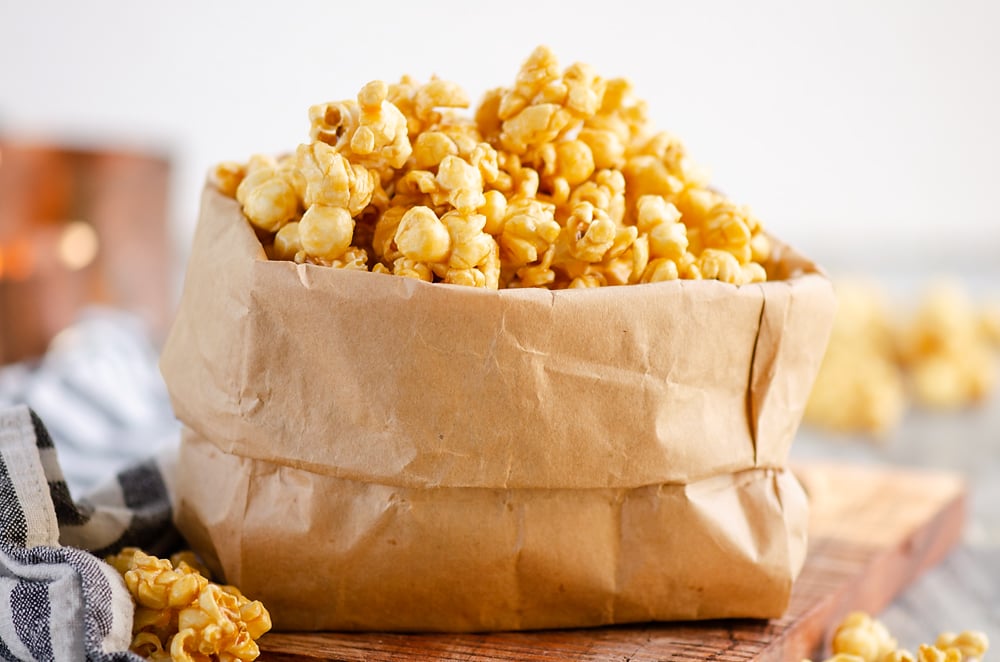 Microwave Caramel Popcorn in a brown paper bag on table with cloth napkin