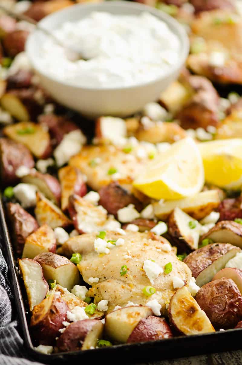 Lemon Feta Sheet Pan Chicken Thighs & Potatoes with bowl of yogurt sauce