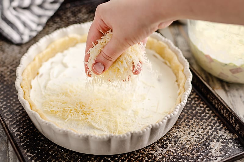 Ham and Goat Cheese Quiche being sprinkled with cheese