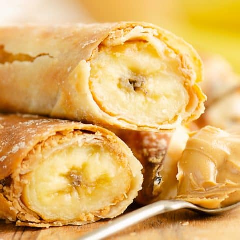 Peanut Butter Banana Egg Rolls stacked with a spoonful of peanut butter