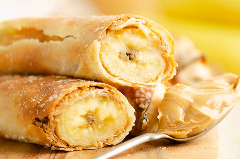 Peanut Butter Banana Egg Rolls stacked with a spoonful of peanut butter