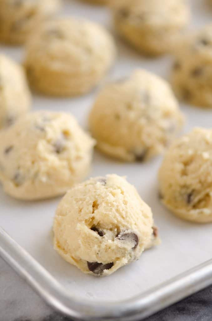 Frozen Chocolate Chip Cookie Dough Pucks arranged on parchment paper on baking sheet