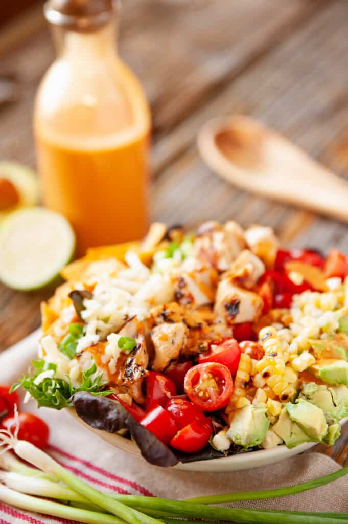 southwest cobb salad on table with bottle of chipotle lime dressing