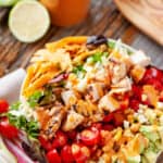 southwest chicken cobb salad in white bowl on table with veggies and napkin