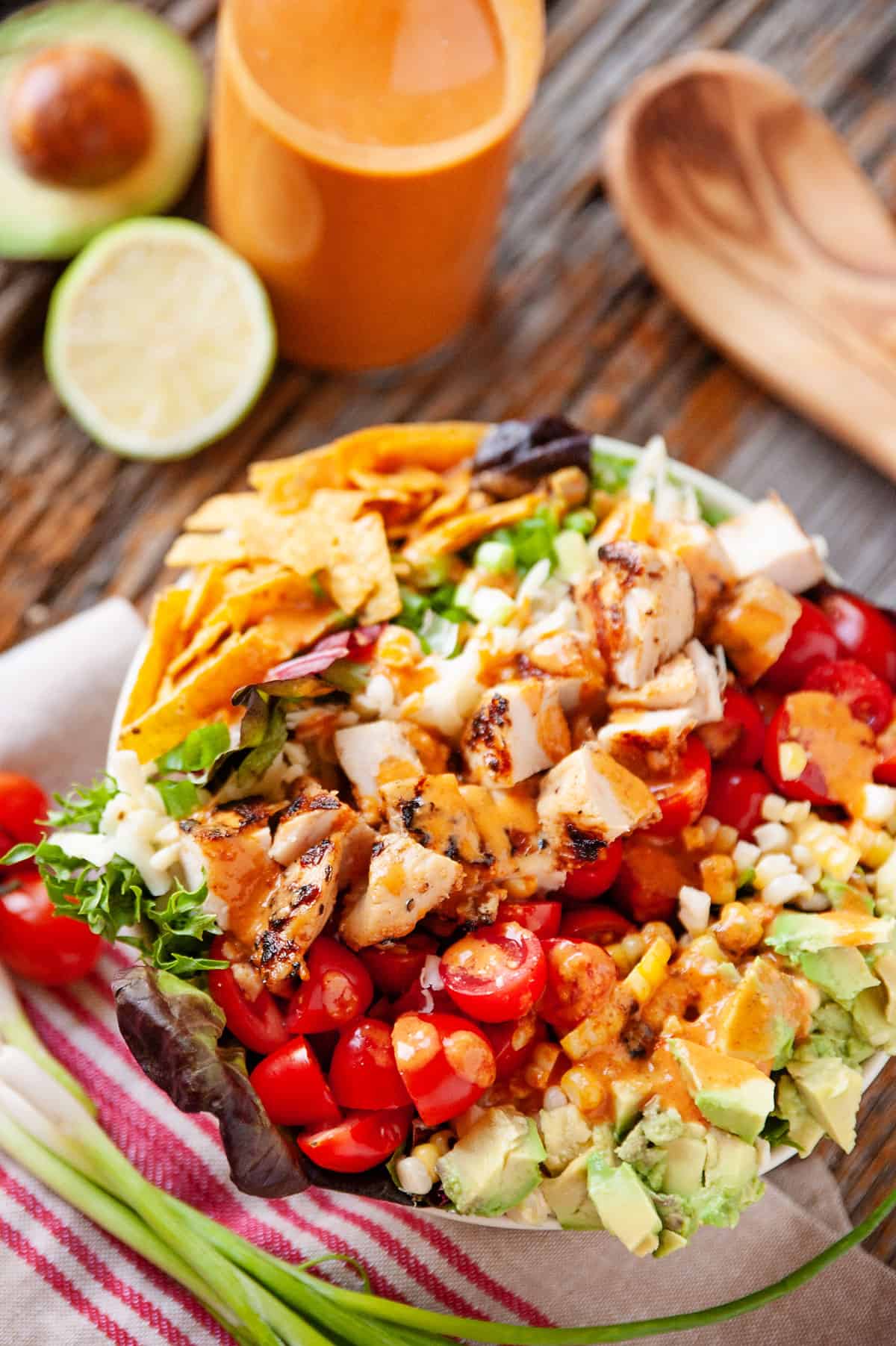 southwest chicken cobb salad in white bowl on table with veggies and napkin