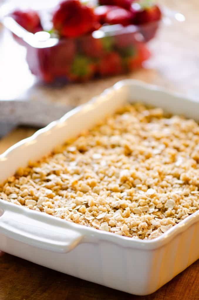 Strawberry Rhubarb Crisp Bars on kitchen counter with strawberries