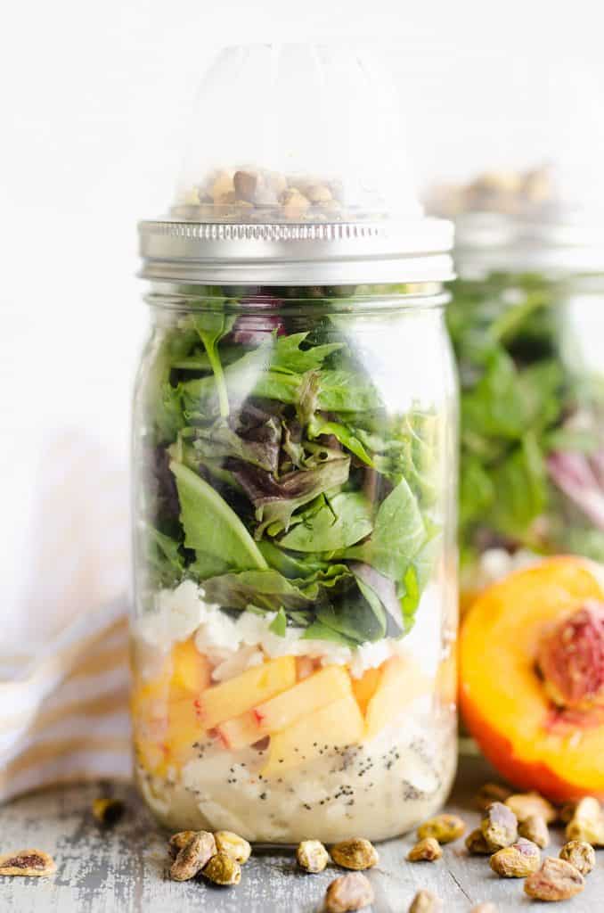 Chicken Peach Salad in a Jar on table with pistachios and fresh peaches