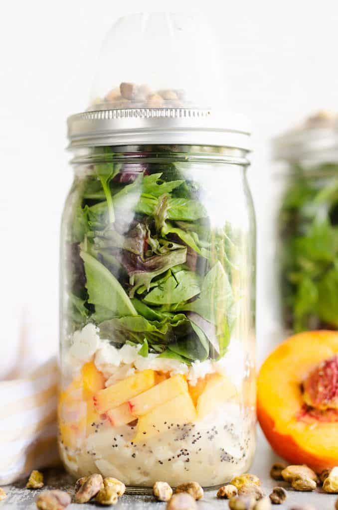 Chicken Peach Salad in a Jar on table with pistachios and fresh peaches