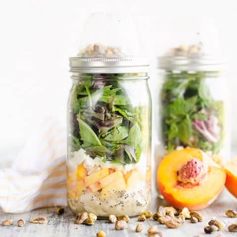 Chicken Peach Salad in a Jars on a table with pistachios and half peaches