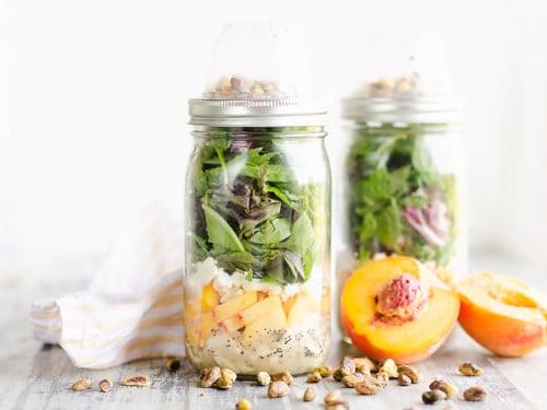 Chicken Peach Salad in a Jars on a table with pistachios and half peaches